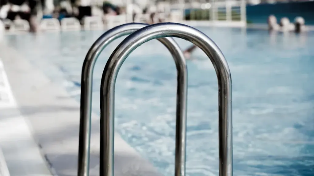 Gros plan sur une échelle métallique au bord d'une piscine publique.