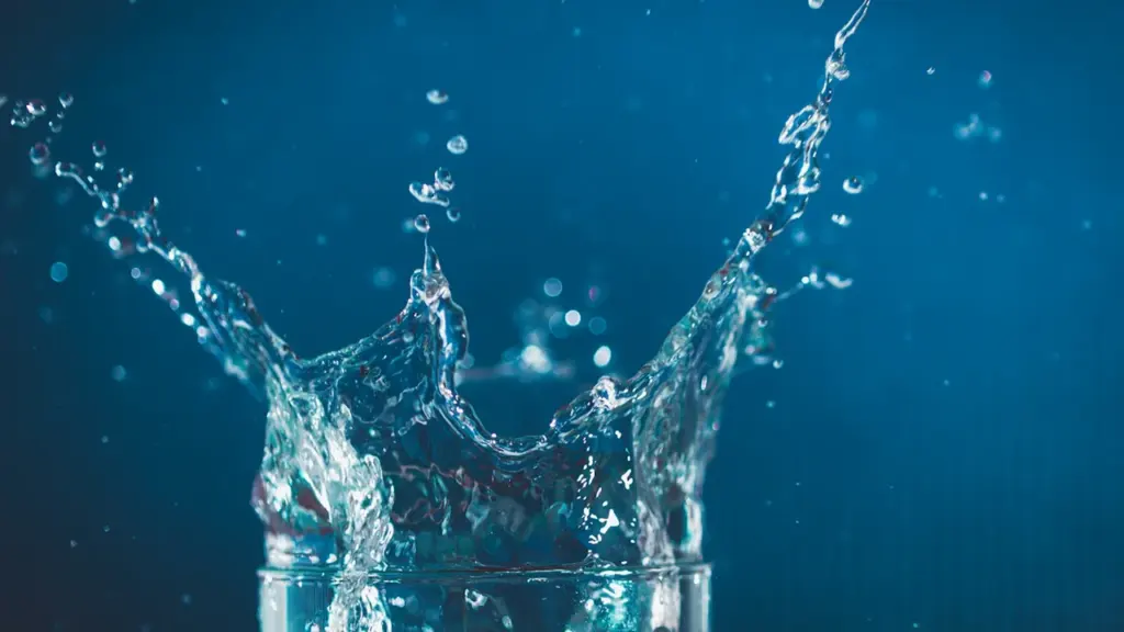 Un verre d'eau clair avec une éclaboussure sur un fond minimaliste.