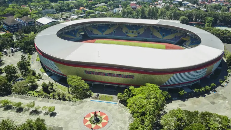 Vue aérienne d'un grand stade moderne entouré de verdure en extérieur.