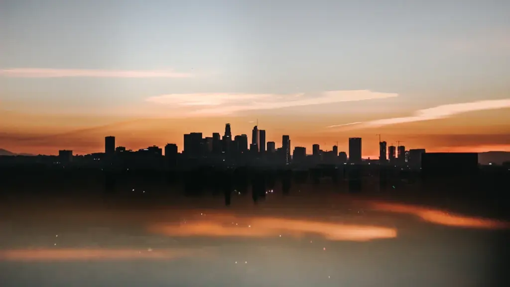 Vue panoramique d'une silhouette urbaine au coucher du soleil sur fond de ciel orangé.