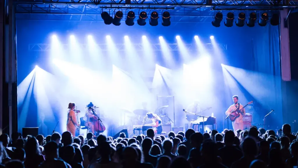 Un groupe de musiciens se produit sur une scène éclairée lors d'un concert nocturne.