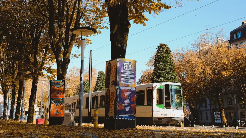 Un tramway circulant dans une rue de Nantes bordée d'arbres en automne.