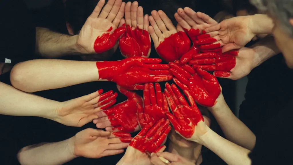 Plusieurs mains peintes en rouge formant un cœur solidaire.
