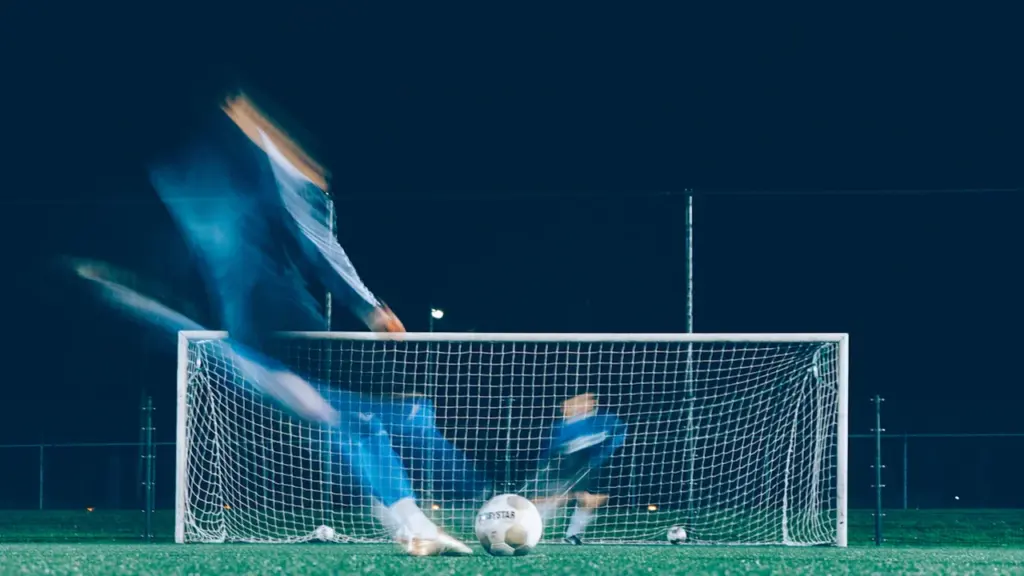 Action de tir au football avec effet de mouvement devant le but.