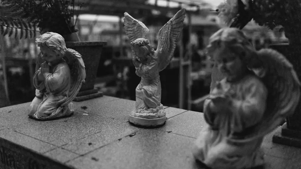 Photographie en noir et blanc de statuettes d'anges ornant un socle en pierre.
