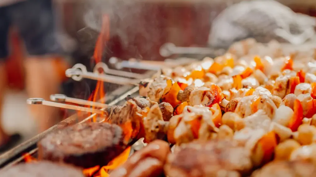 Brochettes de viande et légumes grillant sur un barbecue lors d'une fête en plein air.
