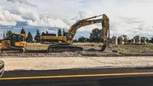 Engins de chantier jaunes effectuant des travaux de rénovation sur une route urbaine.