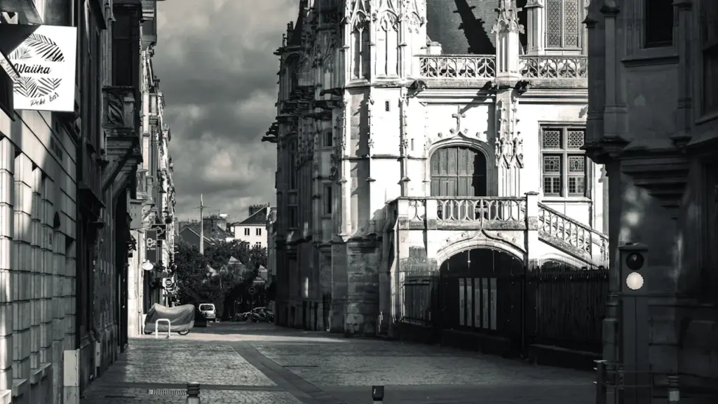 Une rue pavée pittoresque avec des bâtiments historiques à Rouen en noir et blanc.