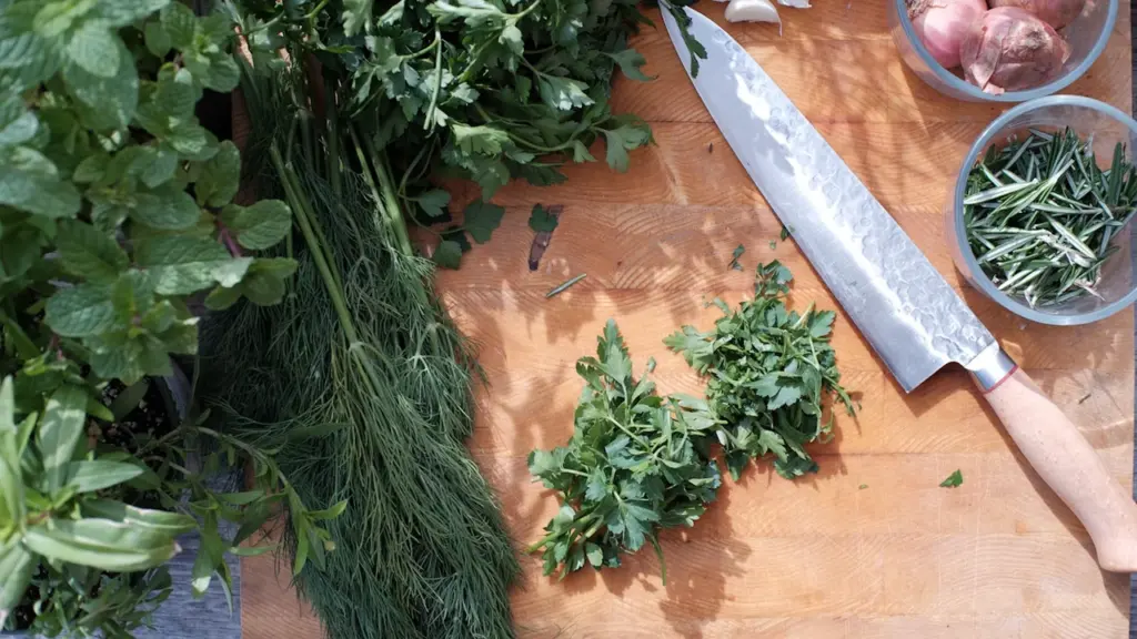Planches à découper avec herbes aromatiques fraîches, ail et un couteau de cuisine.