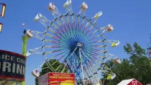 Une grande roue colorée lors d'une fête foraine sous un ciel bleu dégagé.