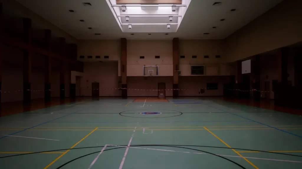 Vue intérieure d'un gymnase municipal avec un terrain de basket et marquages au sol.