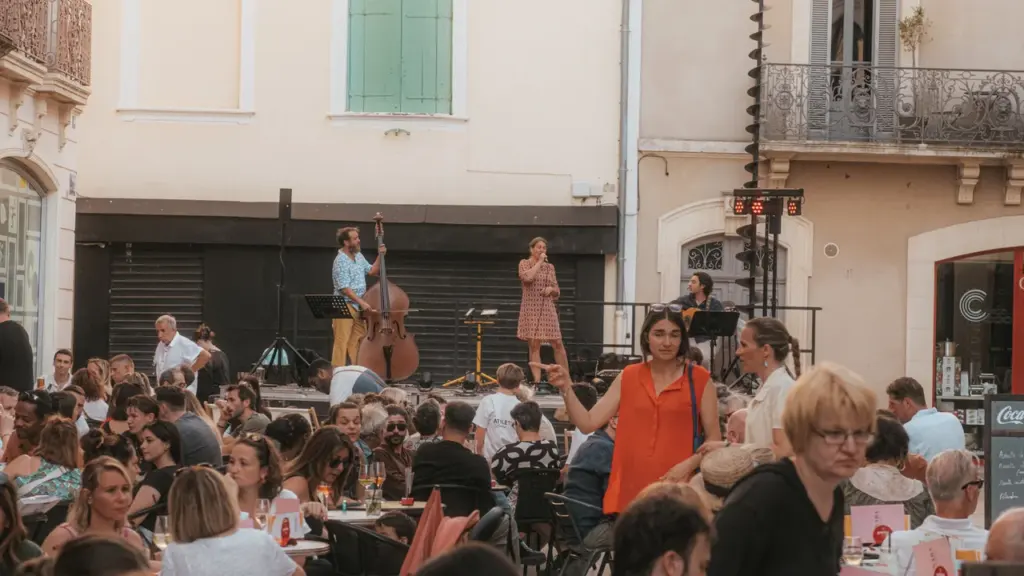 Un groupe de musique joue sur scène devant une terrasse de café bondée en ville.